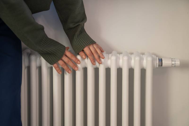 Hands feeling radiator warmth