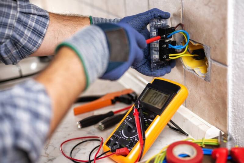 Electrician using multimeter for wiring check.