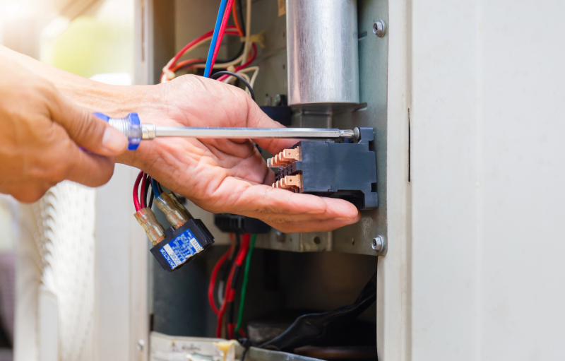 Hand using screwdriver on AC unit wiring