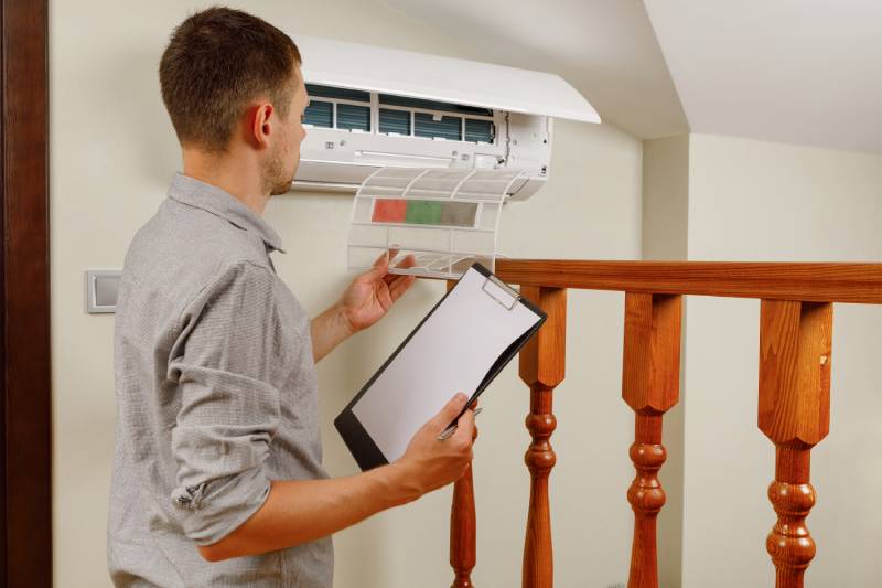 Technician inspecting wall-mounted AC unit.