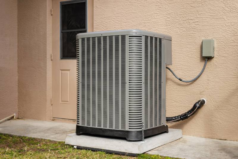 Central AC unit outside home on concrete slab.