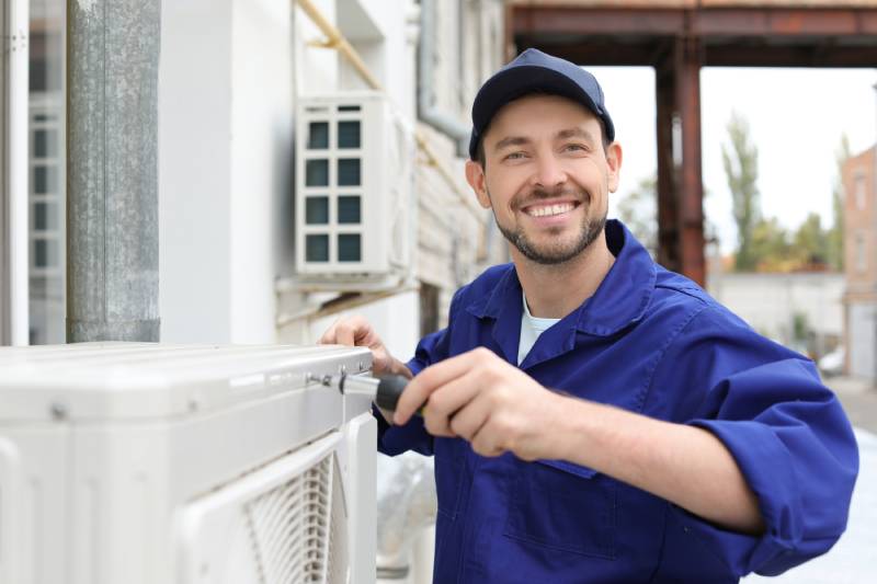 Technician repairing AC unit outdoors.