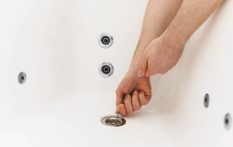 Hands cleaning bathtub drain