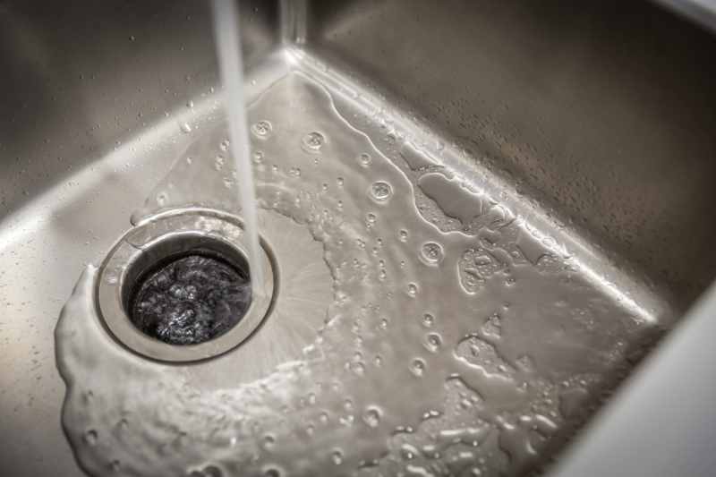 Running water in stainless steel sink with garbage disposal.