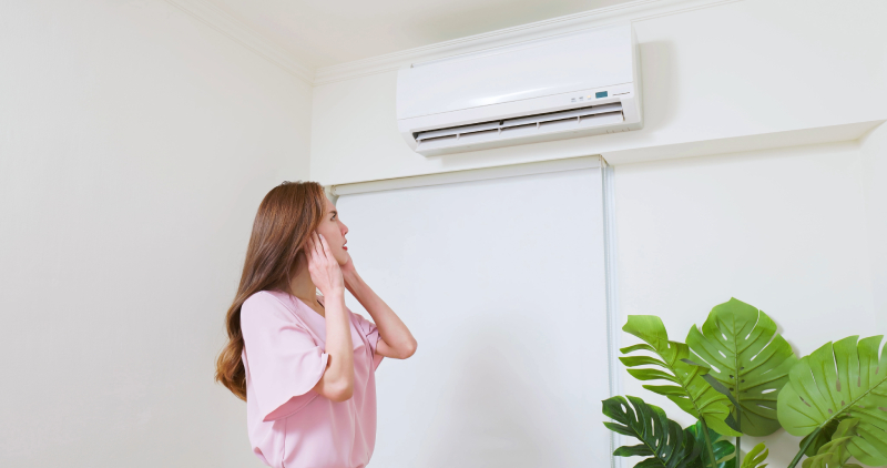 Woman examining wall-mounted AC unit