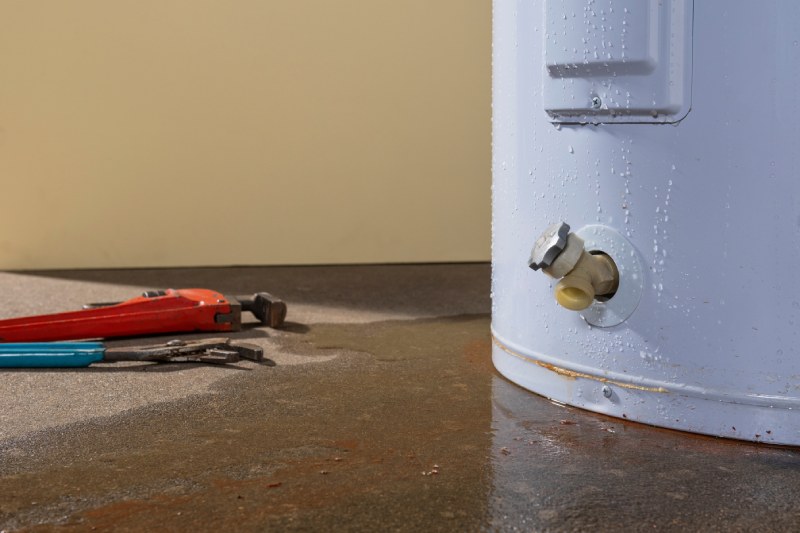 Leaking water heater beside tools.