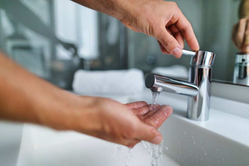 Hands testing water pressure from faucet