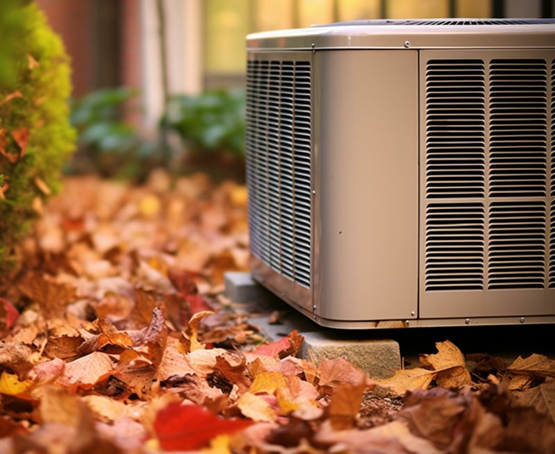 HVAC unit surrounded by autumn leaves