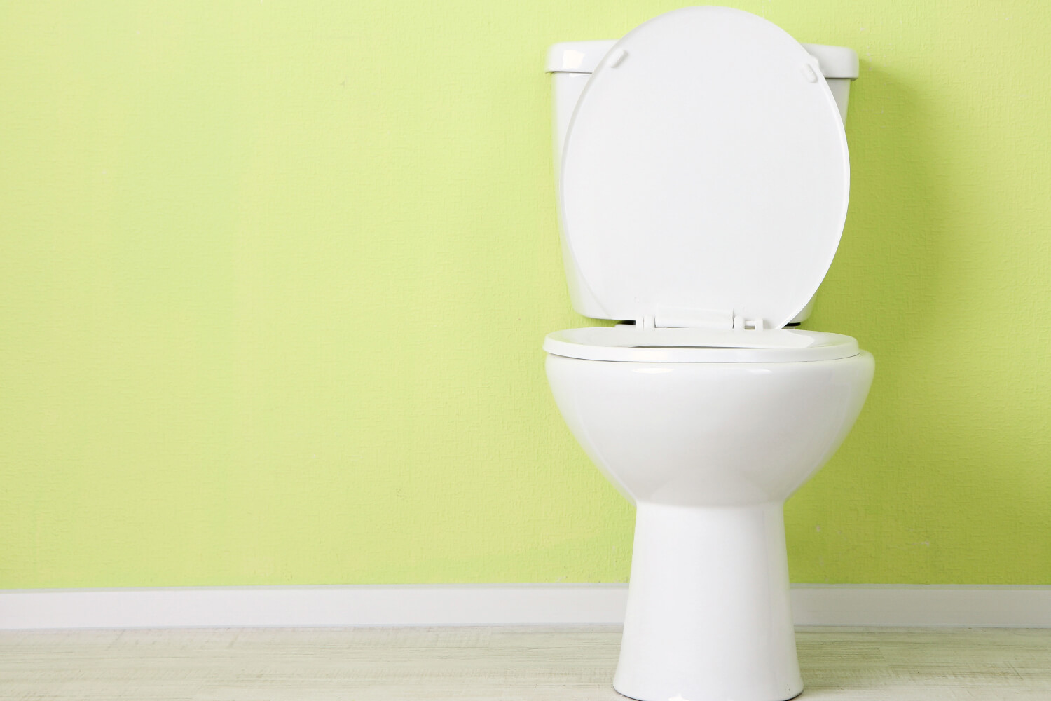 White toilet with open lid against pale green wall background.