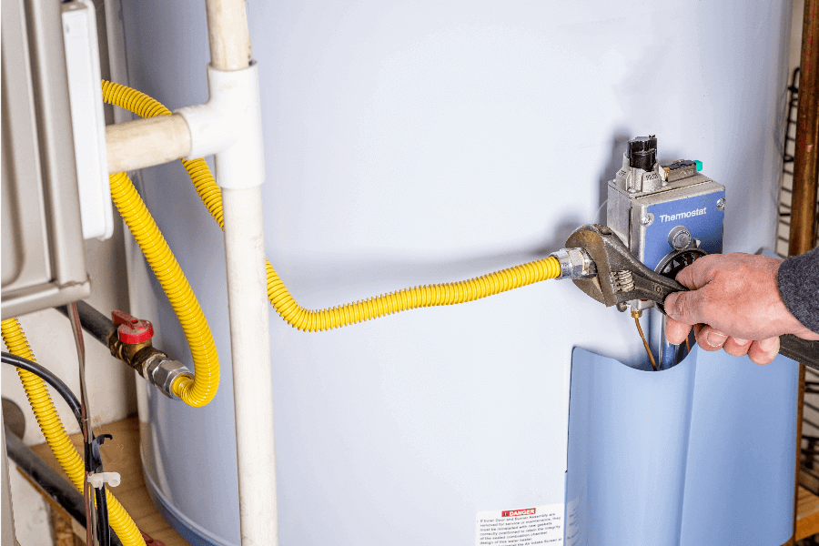 Person adjusting water heater using wrench.