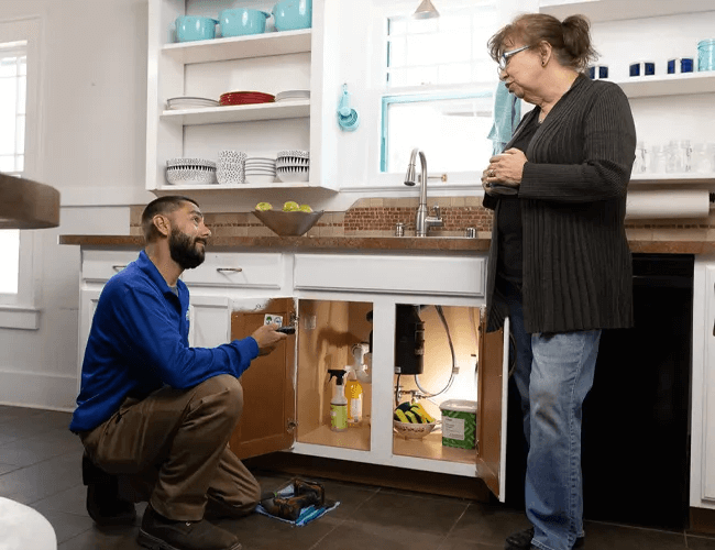 Plumber servicing kitchen sink for homeowner.