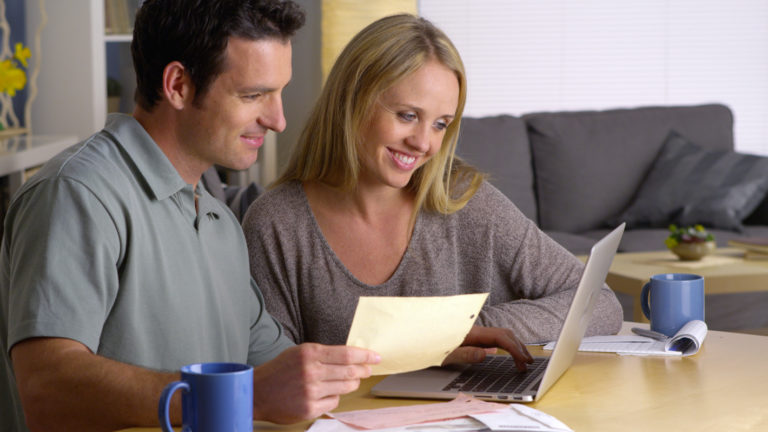 Couple reviewing documents and laptop at home.