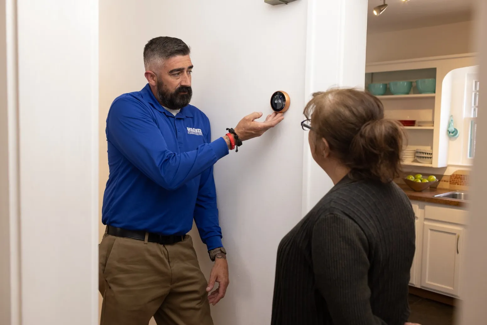 Technician shows woman a smart thermostat.