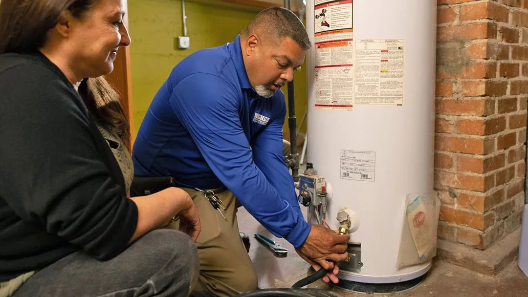 Technician repairs water heater with customer in Albuquerque basement.