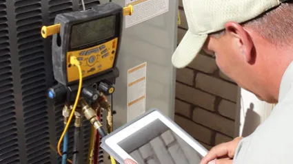Technician inspecting AC unit with tablet.