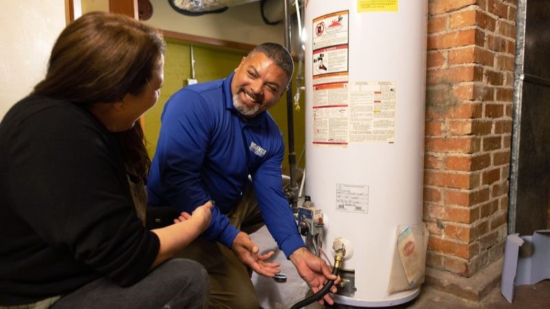 Technician explaining water heater function to a woman.