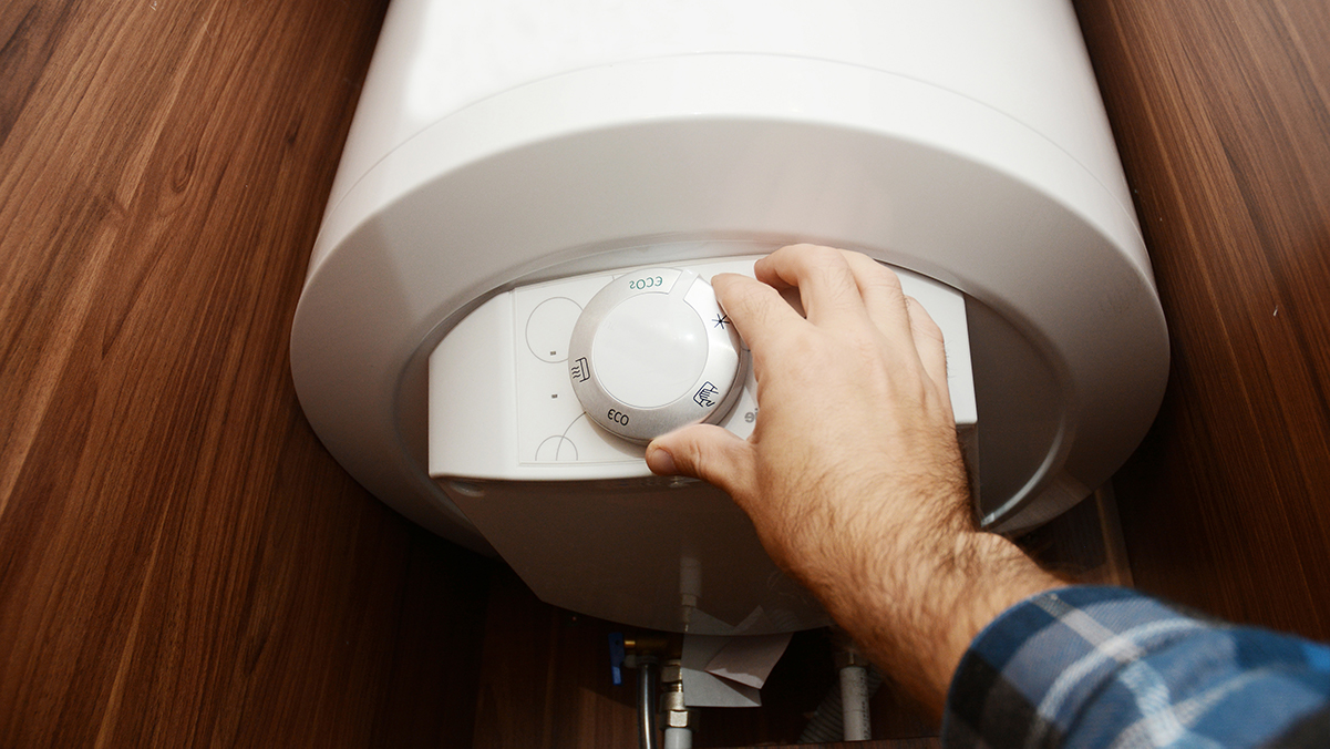 Hand adjusting water heater thermostat.