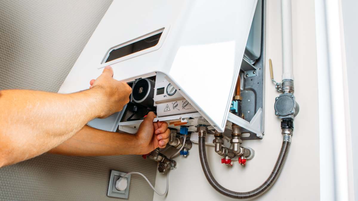 Hands checking inside tankless water heater.