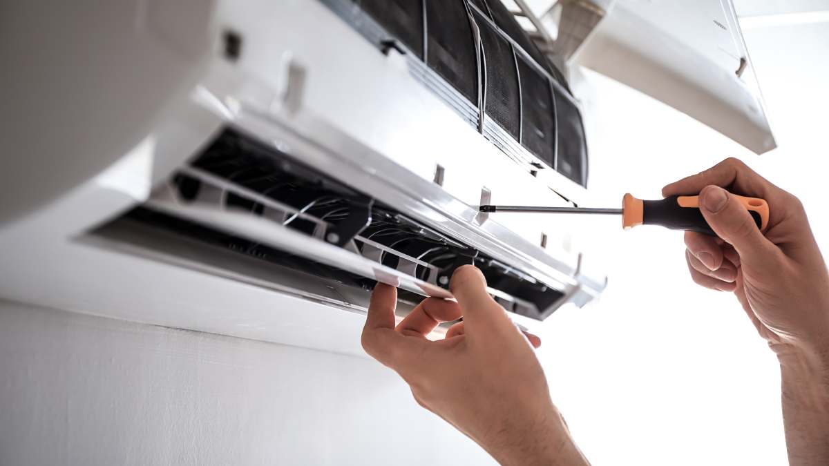 Person servicing air conditioner with screwdriver