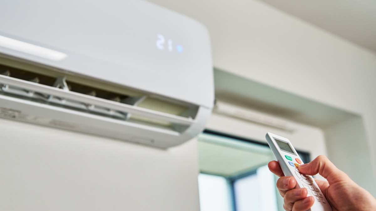 Person adjusting AC unit with remote
