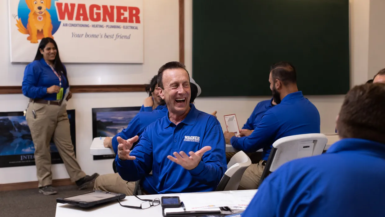 Group of Wagner employees in blue uniforms smiling and talking.