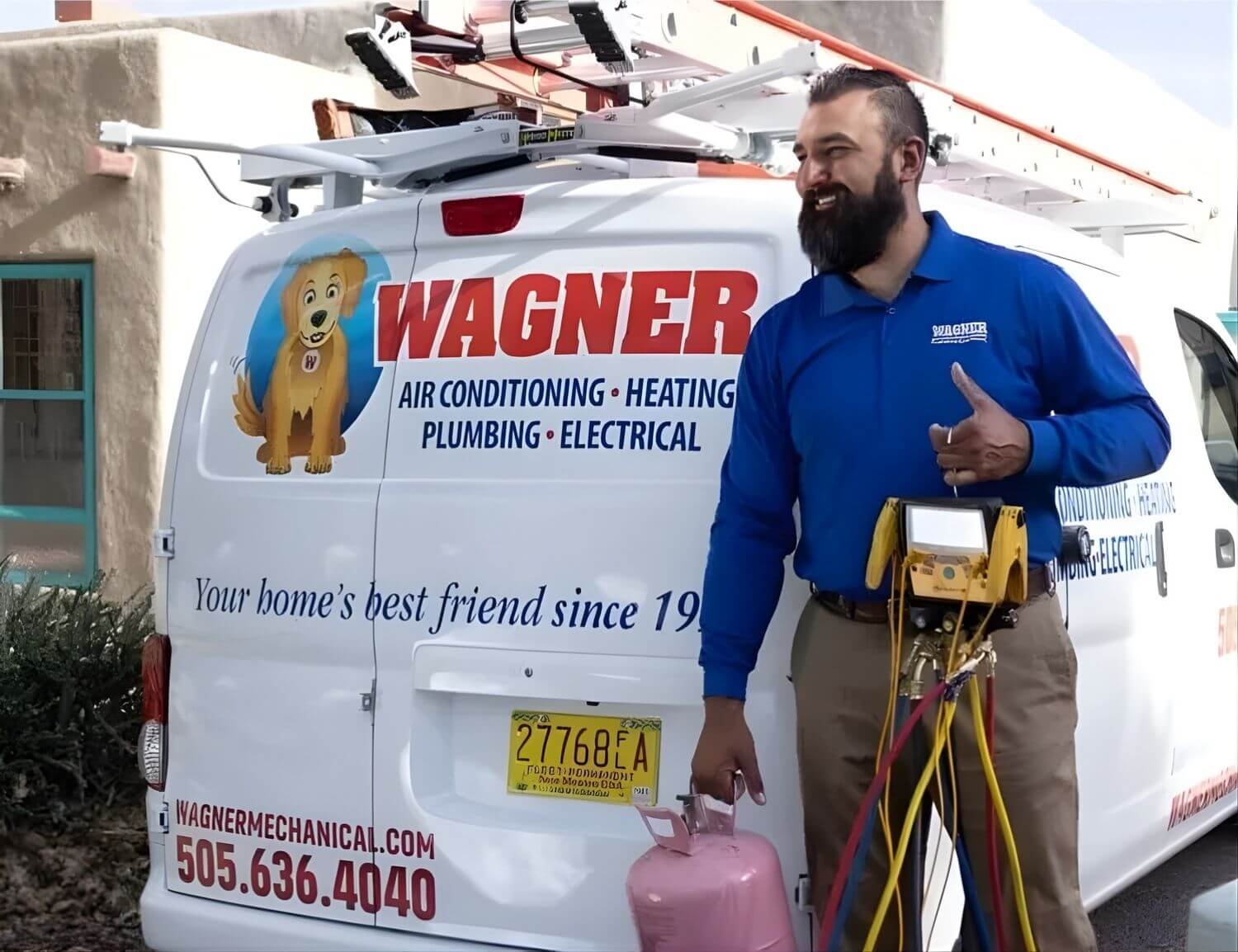 A smiling HVAC technician in a blue Wagner Mechanical shirt stands next to a branded service van holding refrigerant and diagnostic tools. The van displays the company logo with a cartoon dog and advertises air conditioning, heating, plumbing, and electric
