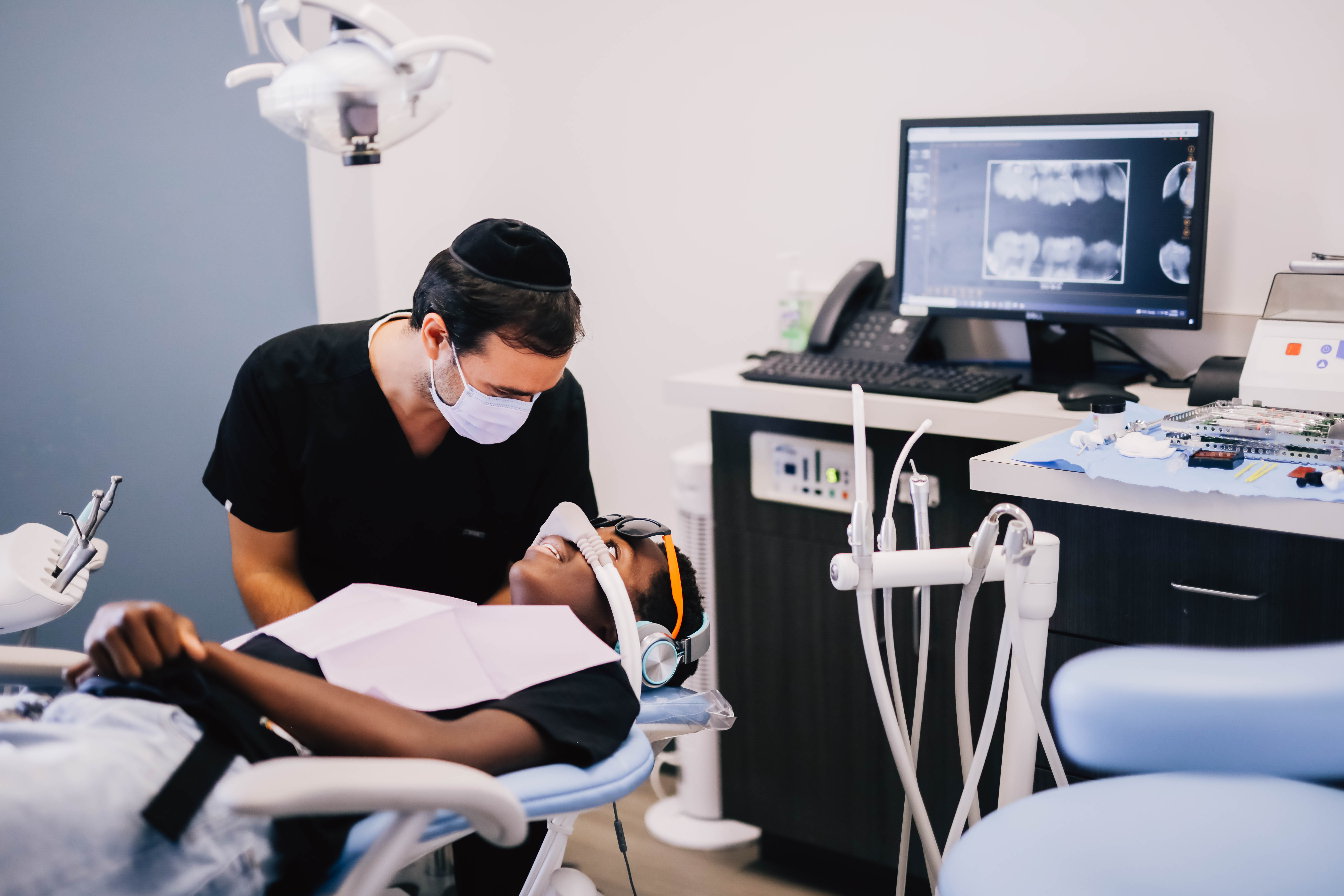 Pediatric dentist examining a child with x-rays on screen at Encinitas Pediatric Dentistry & Orthodontics