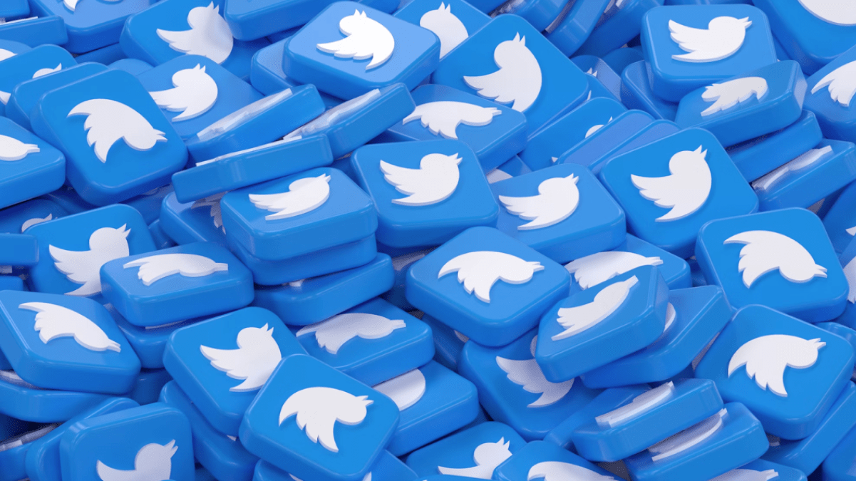 A large pile of glossy blue 3D tiles featuring the classic white Twitter bird logo, symbolising the crowded and fast-moving nature of online discussions and debates on the platform.