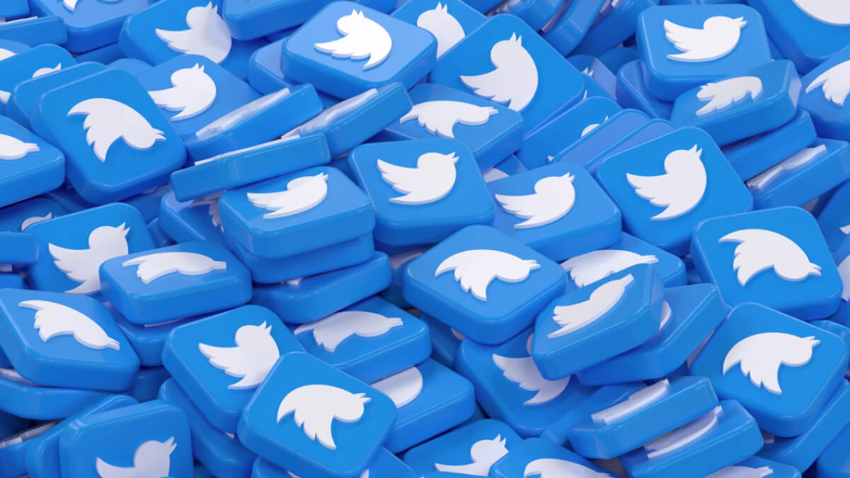 A large pile of glossy blue 3D tiles featuring the classic white Twitter bird logo, symbolising the crowded and fast-moving nature of online discussions and debates on the platform.