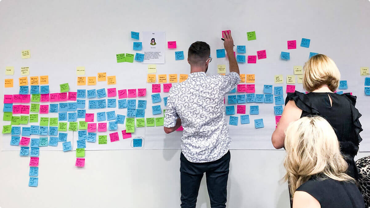 Airteam's delivery manager working on a software development project, standing at a board showcasing a UX research.