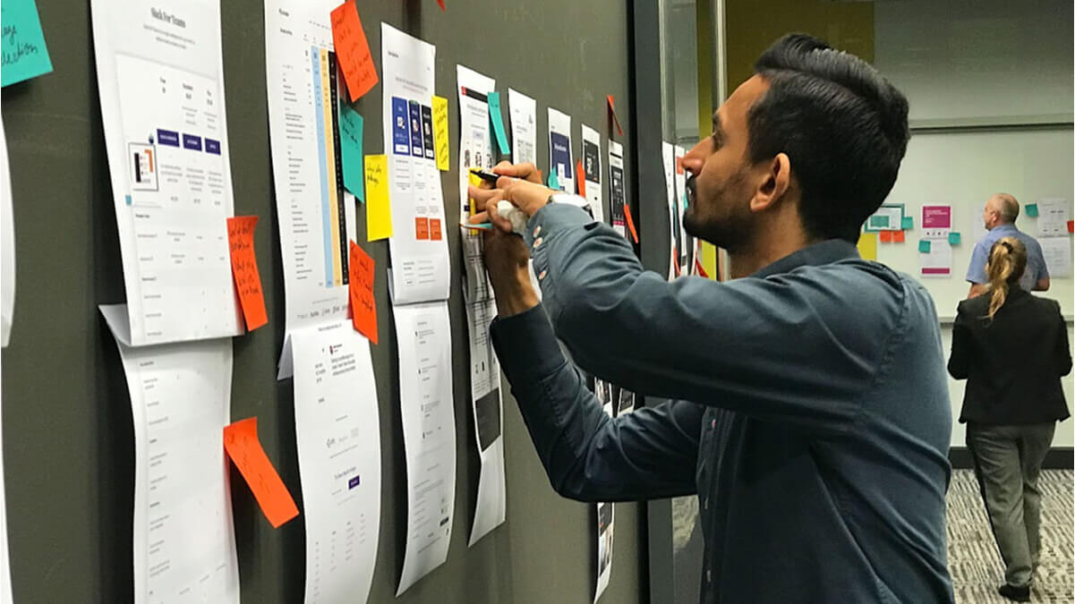 An AIrteam client collaborating on a piece of UX work by providing notes on a post it note.