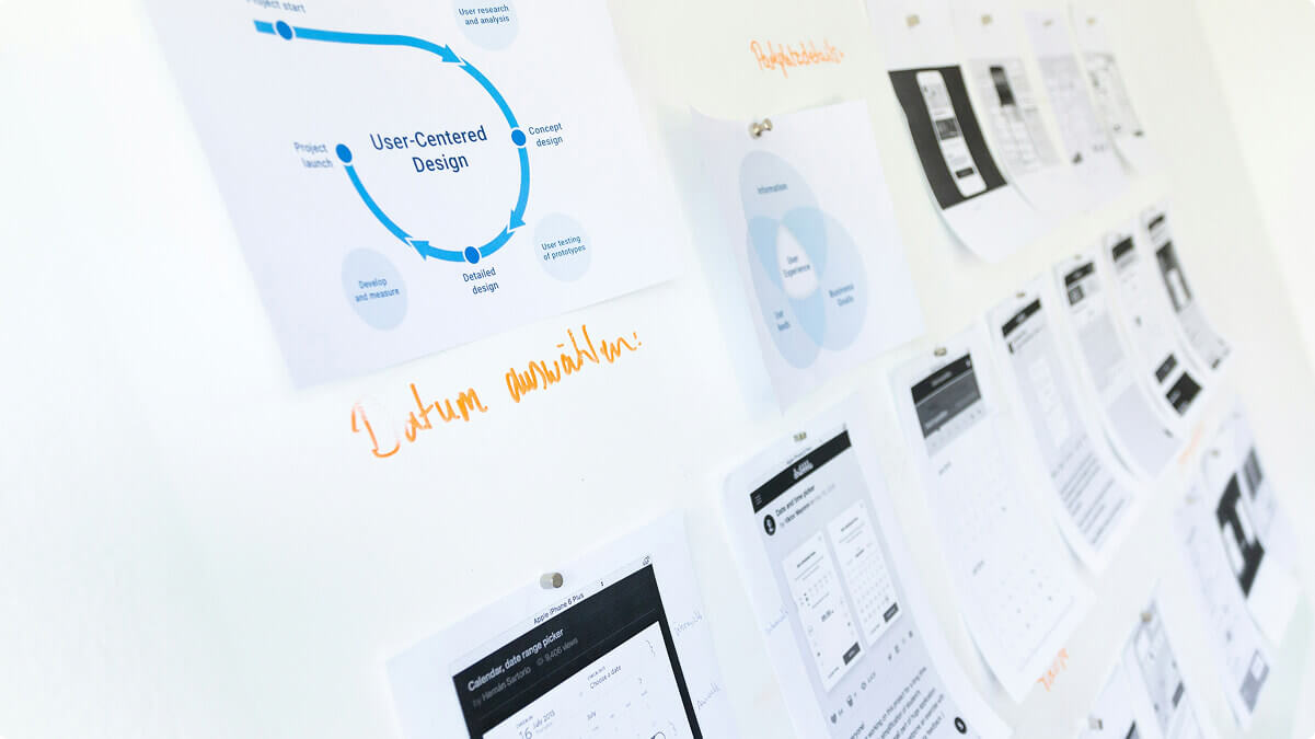 A wall with papers tacked on it, the most visible one says "user-centred design".