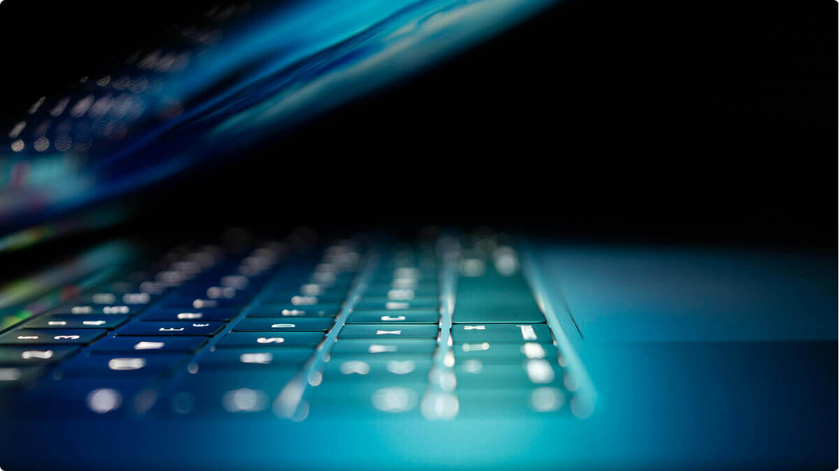 A half closed laptop with a glow coming off the screen.