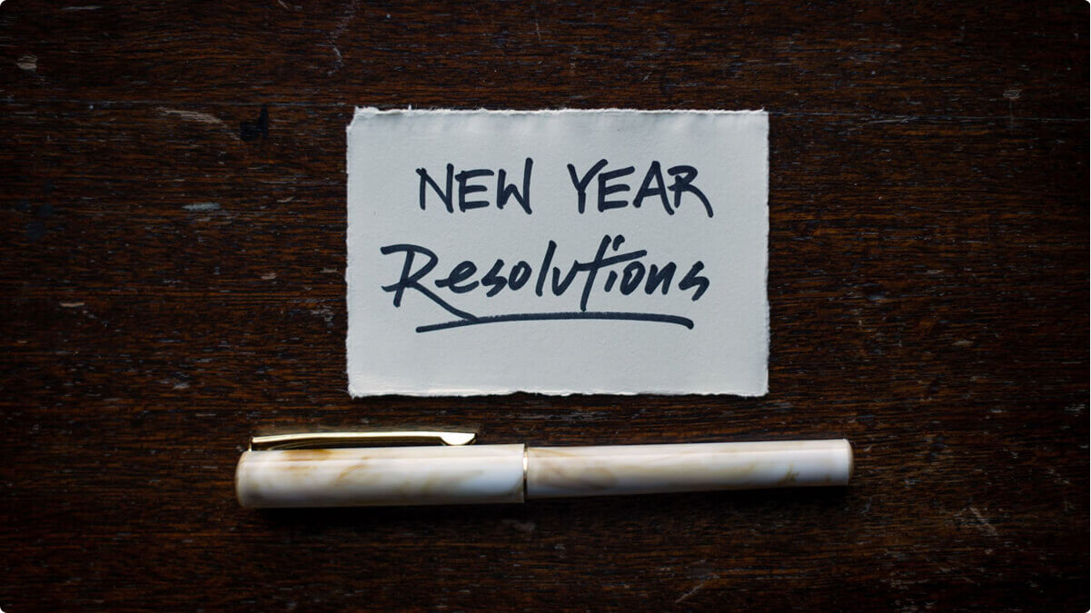 A piece of paper that says "New Years Resolutions" with a pen underneath it.