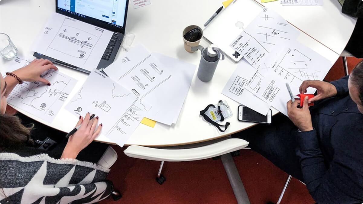 Airteam team members working collaboratively in a Sydney office at a desk with laptops and papers in front of them.