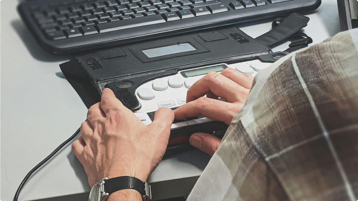 Person in a checkered shirt typing on an accessibility keyboard.