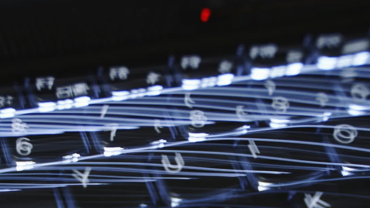 A blurred close-up of a computer keyboard with streaks of light across the keys, creating a sense of speed and motion.