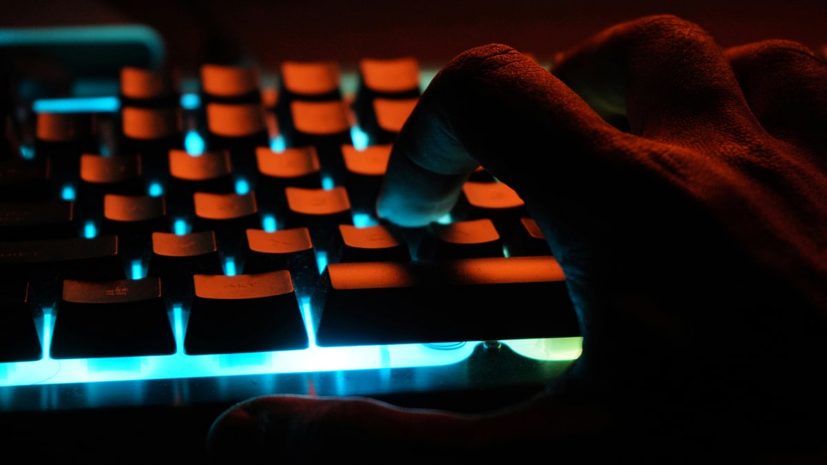 Hand on a glowing keyboard symbolising cyber intrusion and the fragility of data systems in engineering and production.