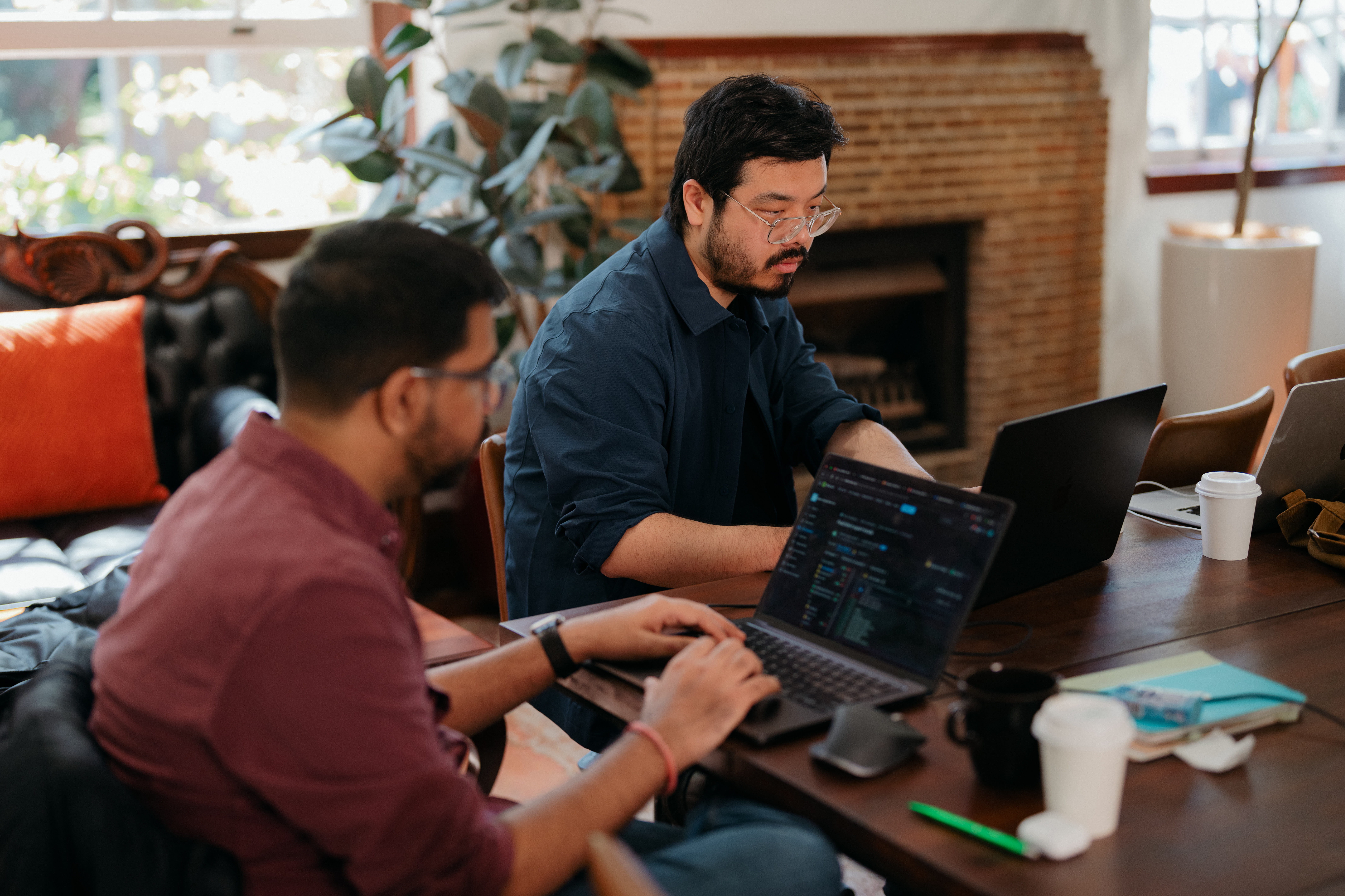 Two software developers working on laptops during a collaborative coding session.