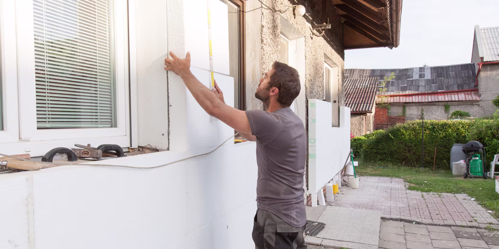 Handwerker installiert während der Kernsanierung eine neue Fassadendämmung an Außenwand