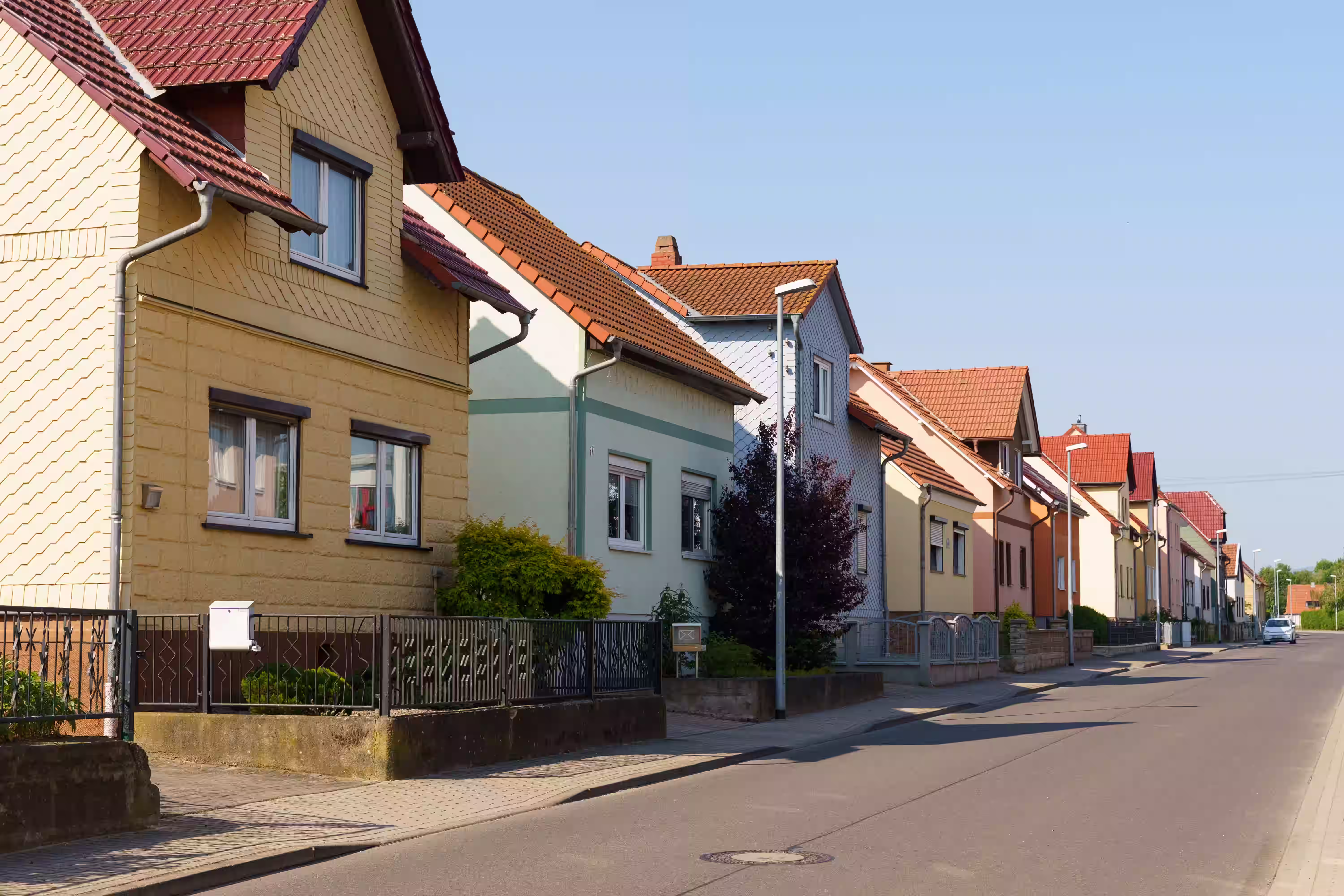 Mehrere bunte Häuser stehen an einer engen Straße in einer Nachbarschaft in der Vorstadt.