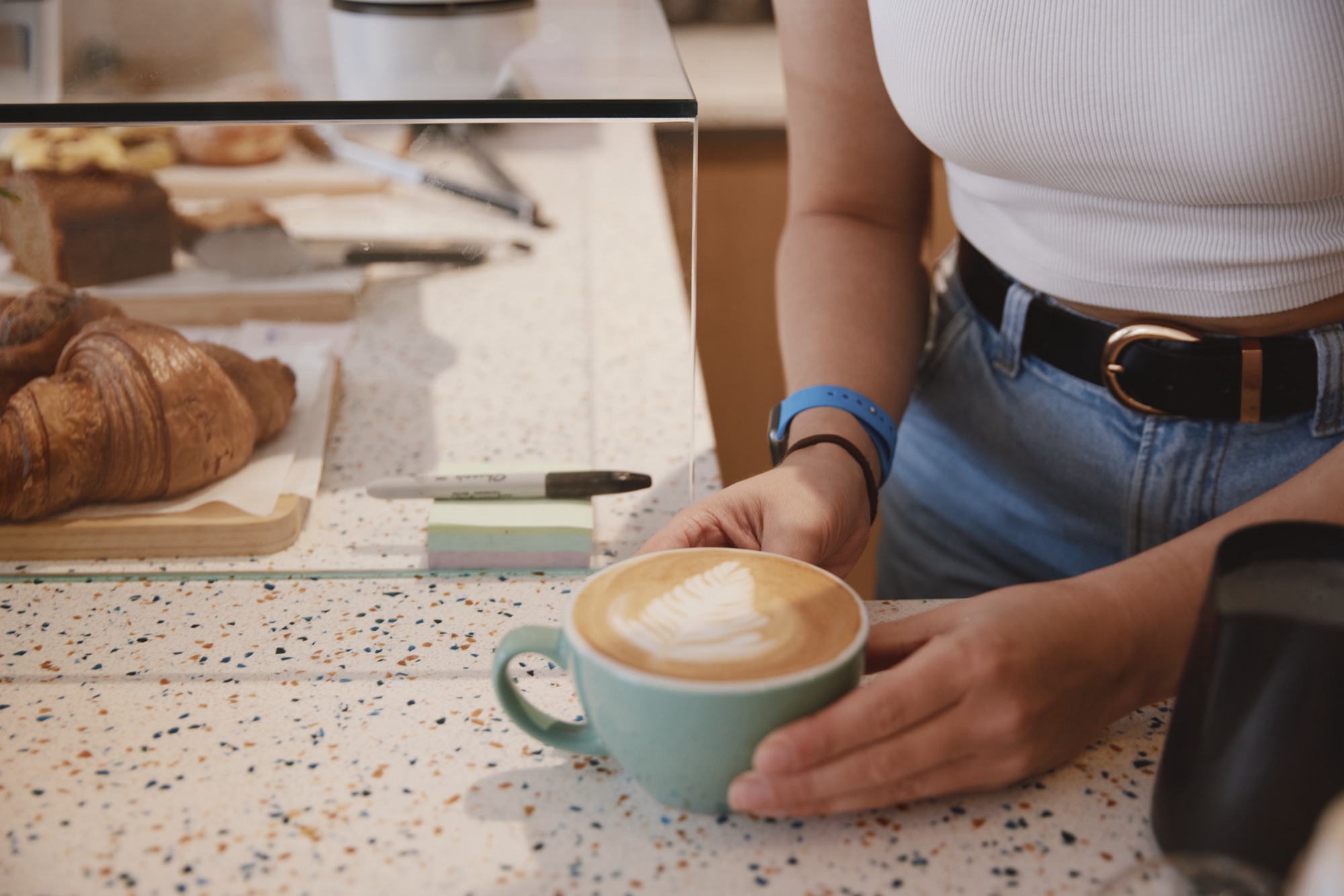 A barista handing over a fresh latte at the Drop-in Richmond caf&eacute;, TW9