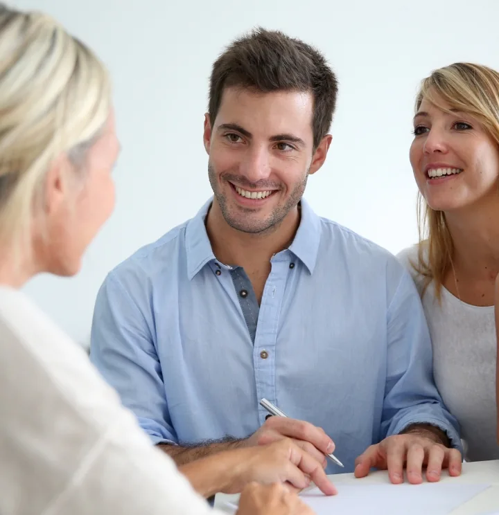 A smiling man and woman as they're signing papers