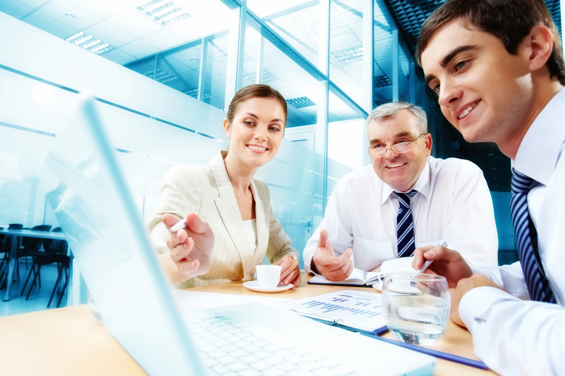 a group of people sitting at a table and looking at a laptop