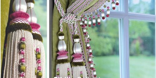 Elegant green curtains adorned with intricate pink and white tiebacks and fringes of Sibilla collection hanging beside a window, offering a glimpse of a lush garden outside.