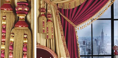 Luxurious red and gold curtains with tiebacks and fringes from Aquirla collection adorn a window, offering a glimpse of a cityscape. The scene exudes opulence and sophistication.