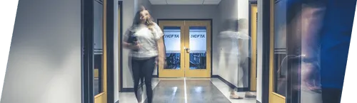 Blurred image of Office workers walking through office hallway holing notebooks.