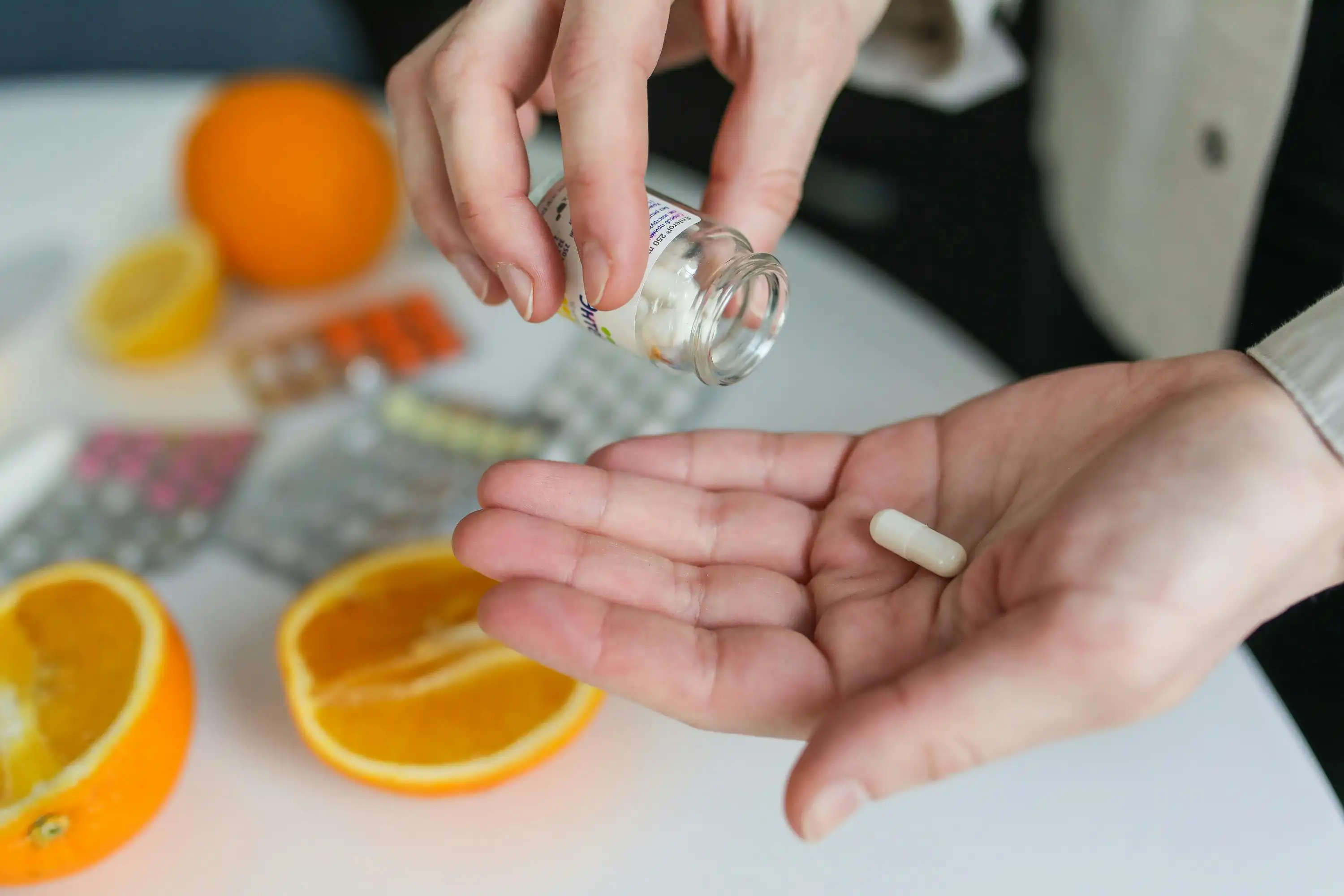 A person's hands with a medicine bottle in one hand and pill and the other hand.