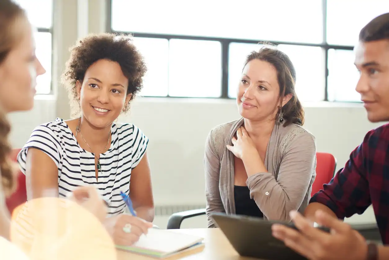 four teachers sitting around a table talking 