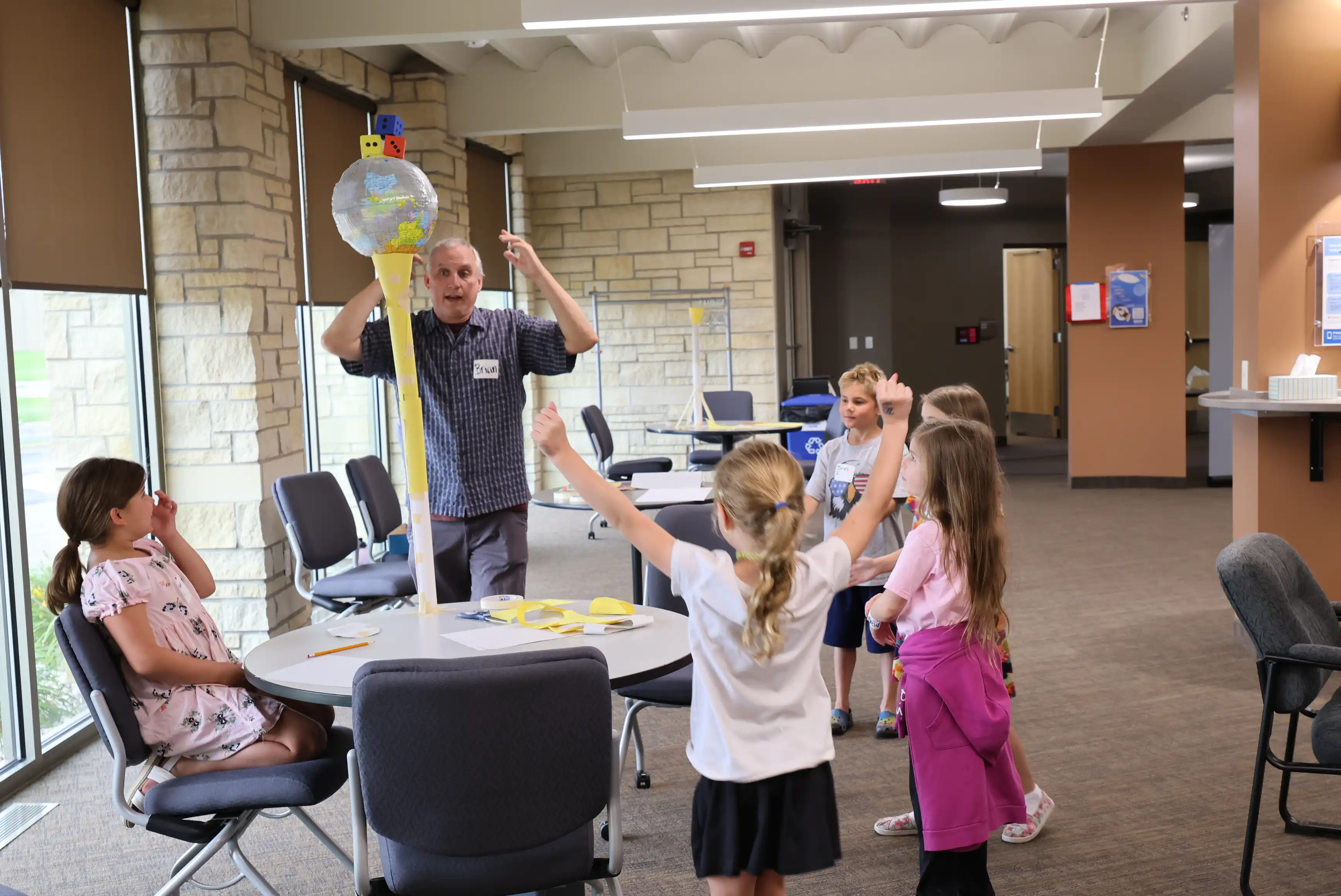 students around a table with an adult holding a globe
